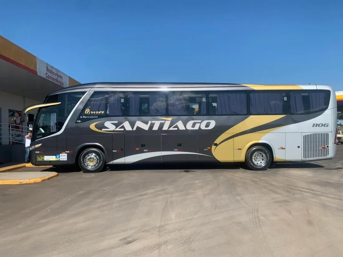 Ônibus executivo da Santiago, cinza com grafismo dourado, abastecendo em um posto de combustível